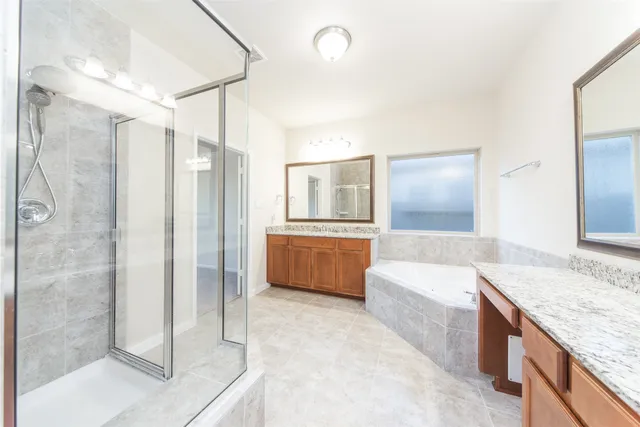a large bathroom with a granite countertop double vanity sink a mirror and a bathtub