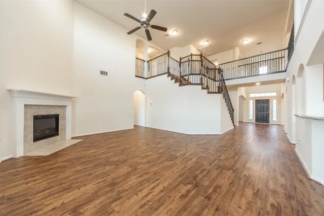 a view of a livingroom with wooden floor a ceiling fan and staircase