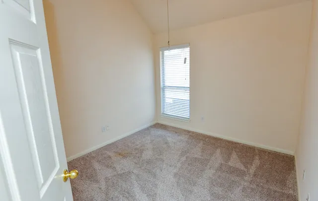 an empty room with chandelier fan and windows