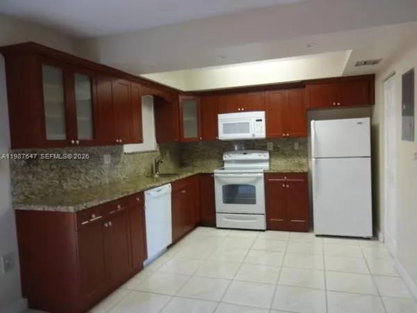 a kitchen with refrigerator and chairs