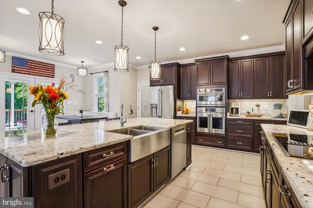 a kitchen with kitchen island granite countertop a stove a sink a oven and a refrigerator with wooden floor