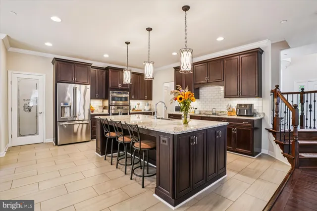 a kitchen with stainless steel appliances granite countertop a stove top oven a sink dishwasher a dining table and chairs with wooden floor