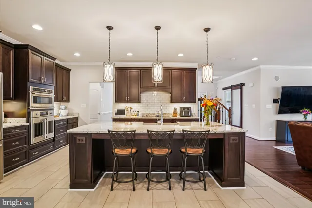 a kitchen with stainless steel appliances kitchen island granite countertop a table chairs and a refrigerator