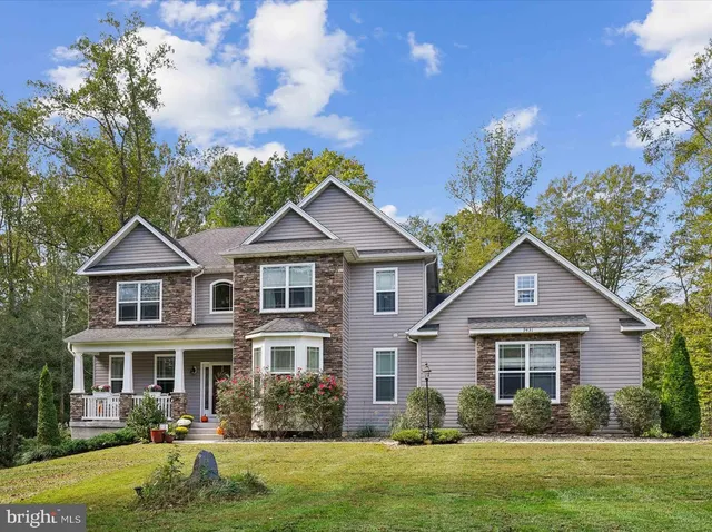 a front view of a house with garden and trees