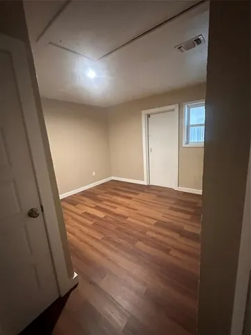 a view of an empty room with wooden floor