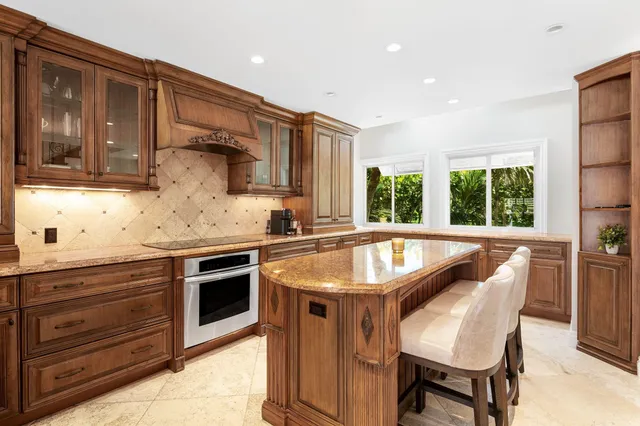 a kitchen with stainless steel appliances granite countertop a table chairs and a refrigerator