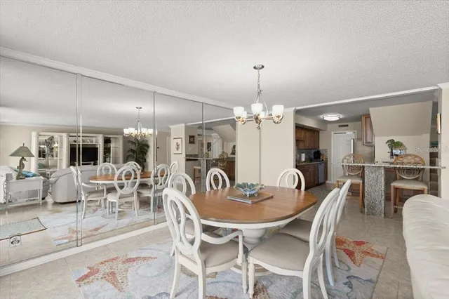 a view of a dining room with furniture a chandelier and kitchen view