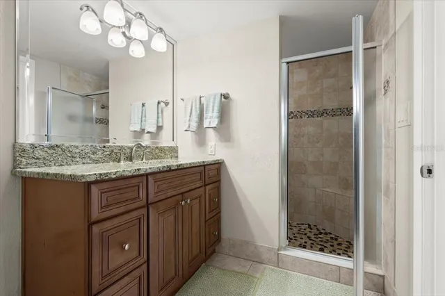 a bathroom with a granite countertop sink a mirror and shower