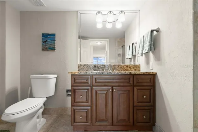 a bathroom with a granite countertop toilet sink and mirror