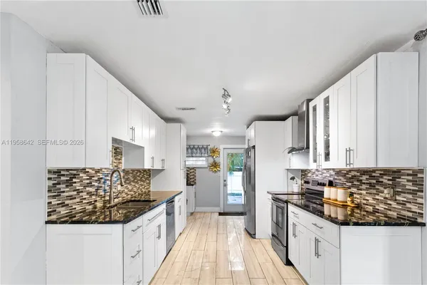 a kitchen with granite countertop a sink stove and cabinets
