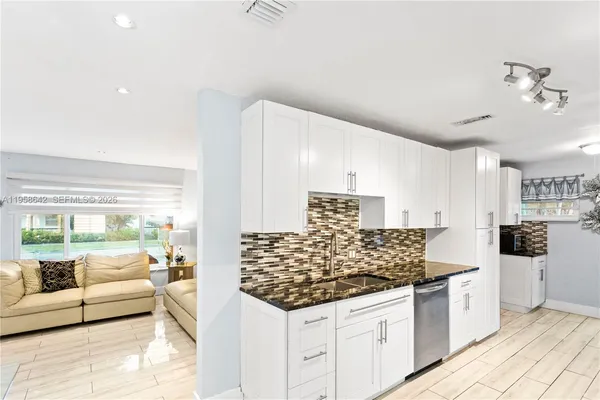 a kitchen with stainless steel appliances kitchen island granite countertop a stove and white cabinets