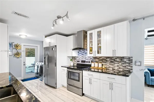 a kitchen with granite countertop a stove cabinets and refrigerator