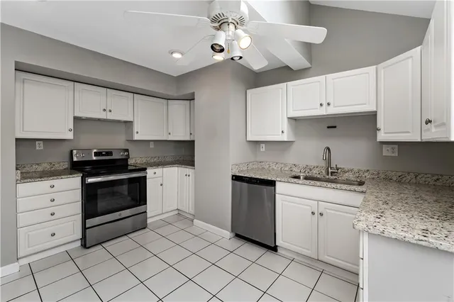 a kitchen with granite countertop white cabinets white stainless steel appliances with a sink and dishwasher