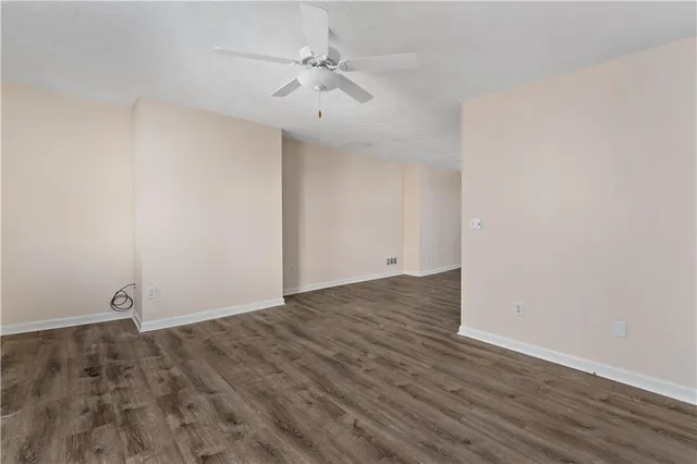 an empty room with wooden floor and fan