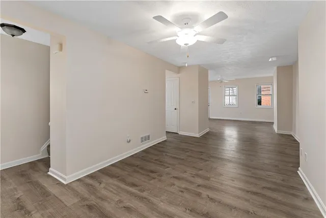 an empty room with wooden floor and ceiling fan
