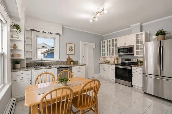 a kitchen with stainless steel appliances granite countertop a stove a sink a refrigerator a stove a dining table and chairs