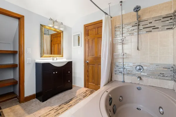 a bathroom with a tub sink and mirror