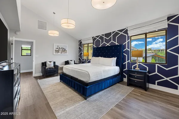 a bedroom with a bed and dresser with wooden floor