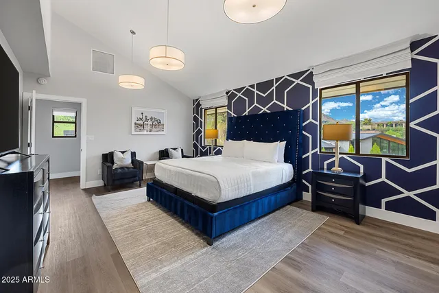 a bedroom with a bed and dresser with wooden floor