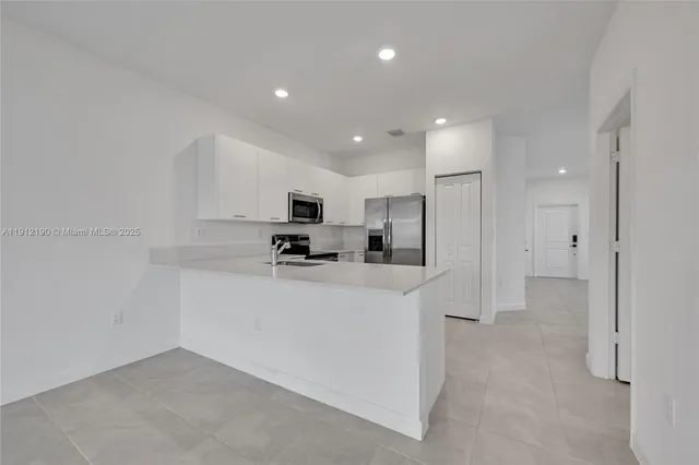 a view of kitchen with stainless steel appliances refrigerator oven and couches