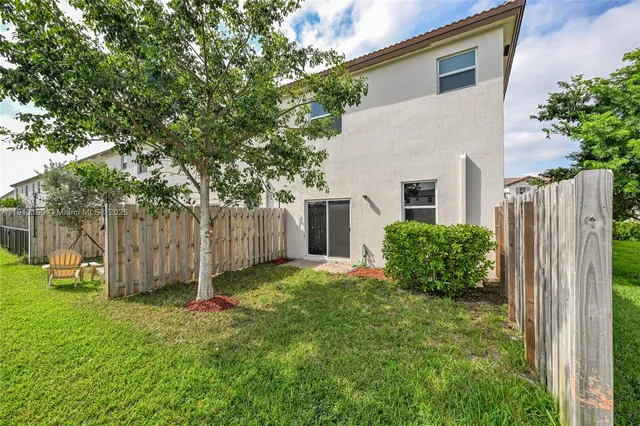 a view of backyard with potted plants and large tree