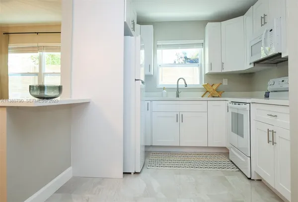 a kitchen with white cabinets and window