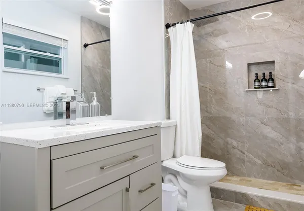 a bathroom with a sink a toilet and shower