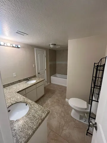 a bathroom with a granite countertop sink a toilet a mirror and shower