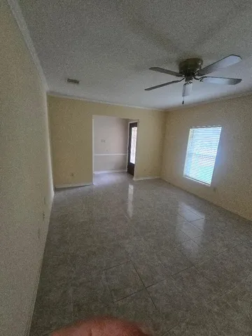 an empty room with windows and ceiling fan