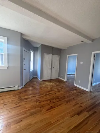 a view of an empty room with window and wooden floor