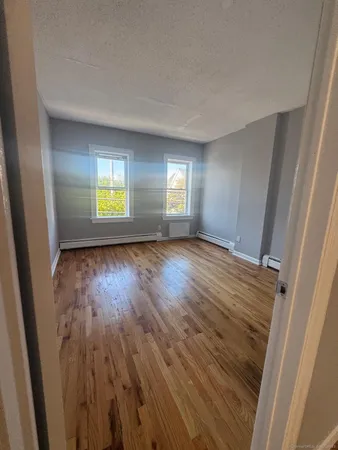 a view of empty room with window and wooden floor