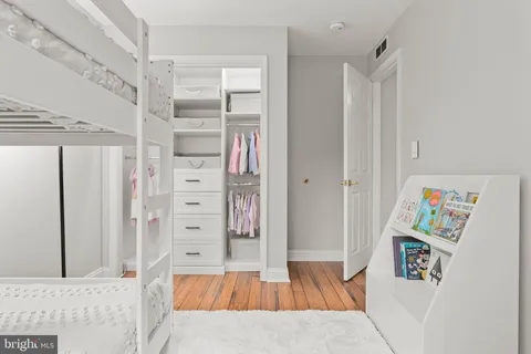 a bedroom with a bed a dresser and next to a window