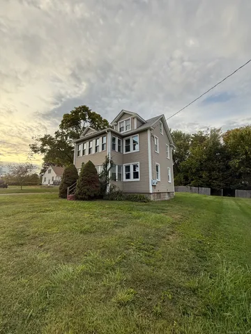 a view of a big house with a big yard and large trees