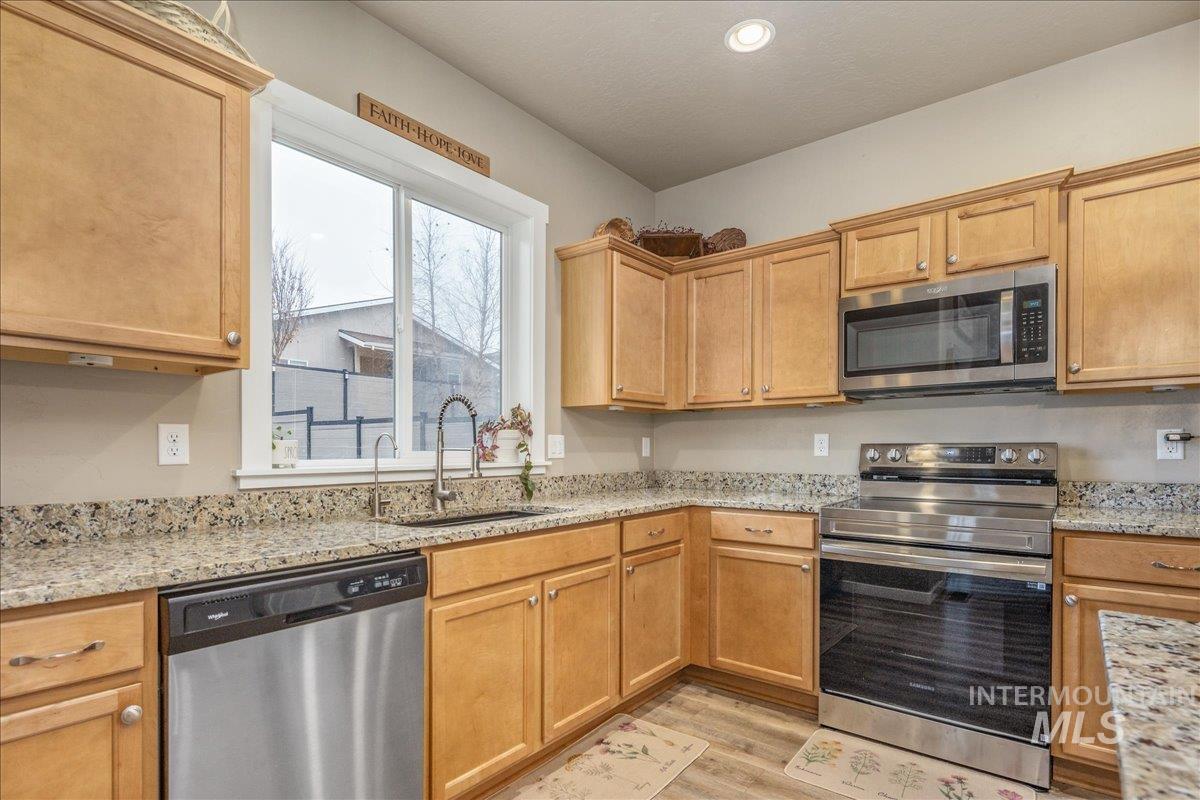 5668 West Old Ranch Street Boise, ID 83714 - Photo 13 of 44 Kitchen featuring stainless steel appliances, light stone countertops, light wood finished floors, and recessed lighting