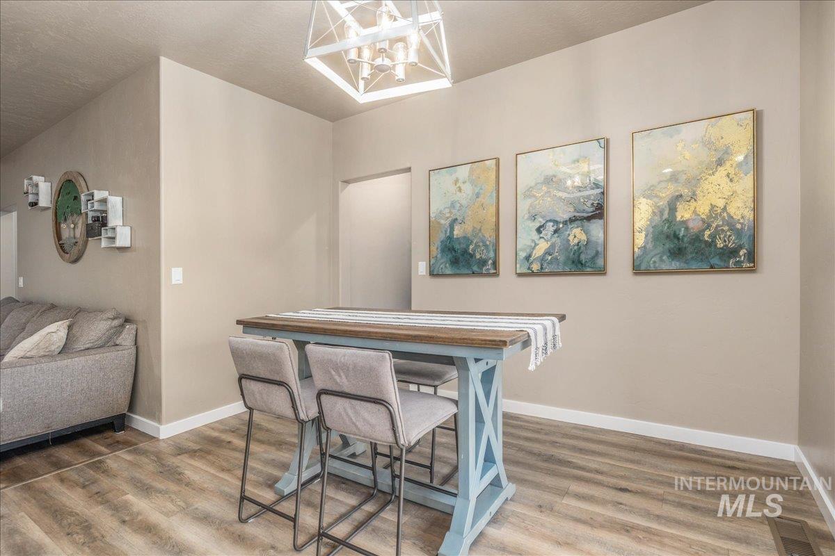 5668 West Old Ranch Street Boise, ID 83714 - Photo 22 of 44 Dining space featuring wood finished floors and a chandelier
