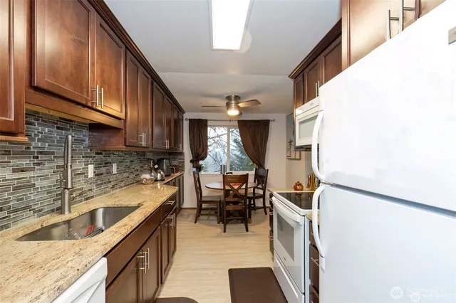 a kitchen with granite countertop a sink a stove and cabinets