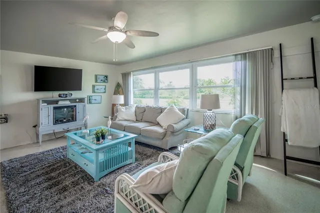 a living room with furniture a flat screen tv and a large window