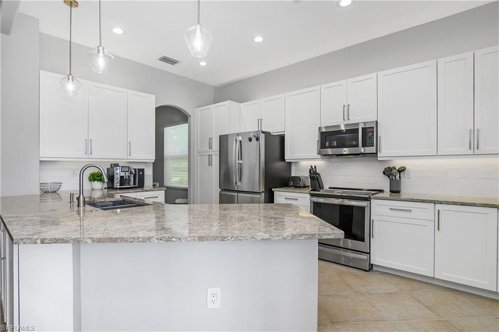 24361 Copperleaf Boulevard Estero, FL 34135 - Photo 11 of 49 a kitchen with stainless steel appliances granite countertop a sink stove and refrigerator