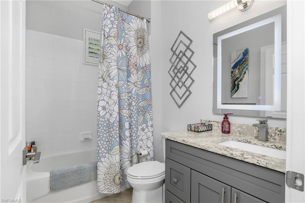 24361 Copperleaf Boulevard Estero, FL 34135 - Photo 21 of 49 a bathroom with a granite countertop sink a toilet and a shower