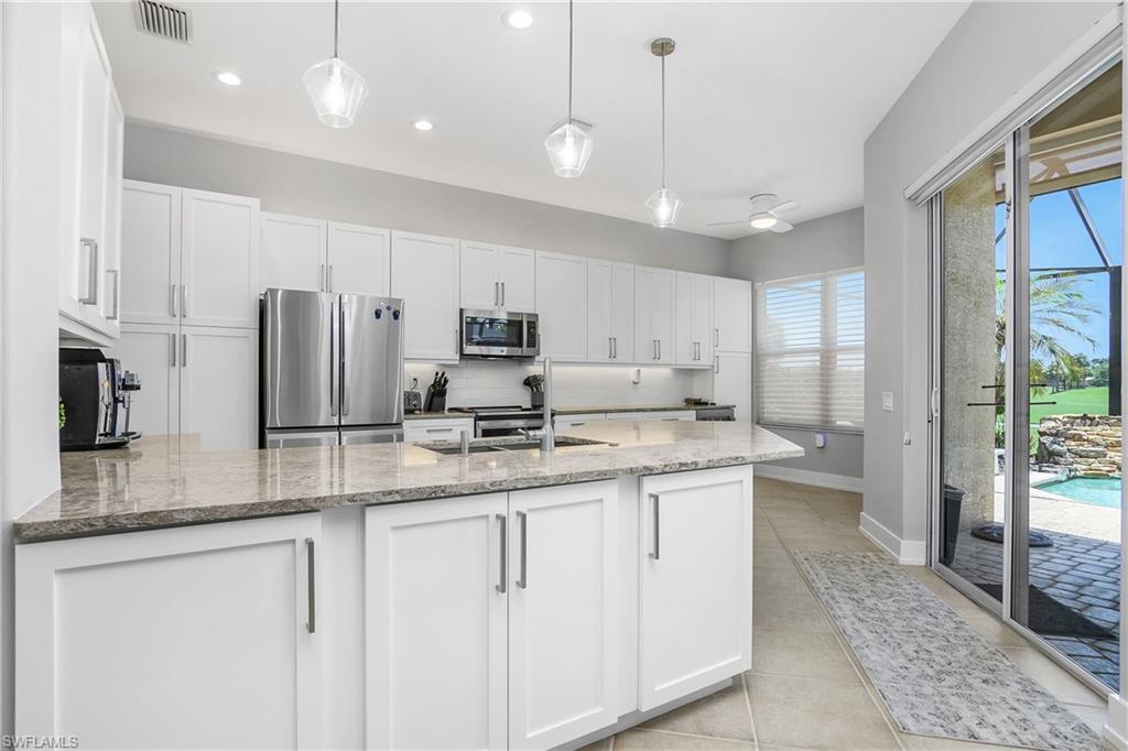24361 Copperleaf Boulevard Estero, FL 34135 - Photo 9 of 49 a kitchen with stainless steel appliances granite countertop a sink a refrigerator and a granite counter tops