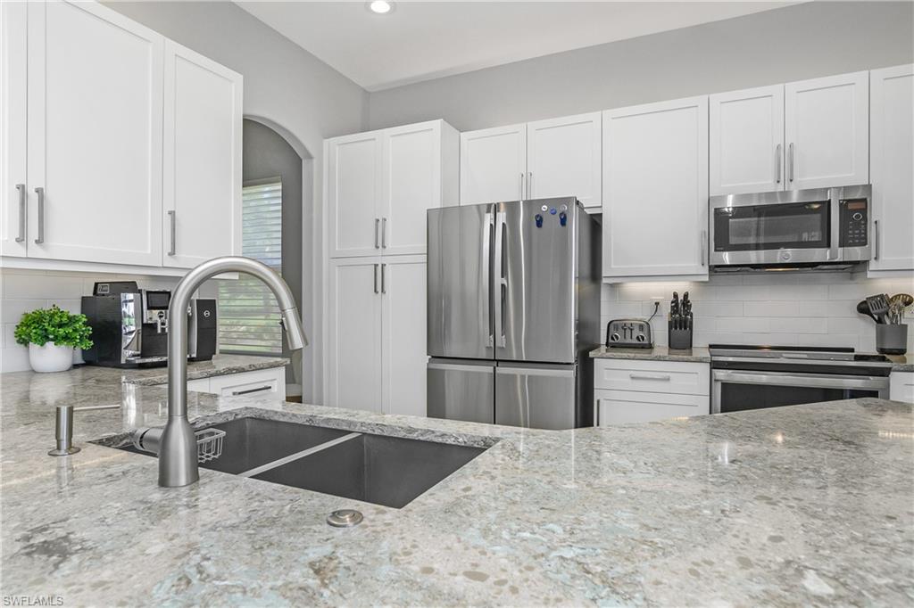 24361 Copperleaf Boulevard Estero, FL 34135 - Photo 10 of 49 a kitchen with granite countertop a refrigerator and a stove top oven