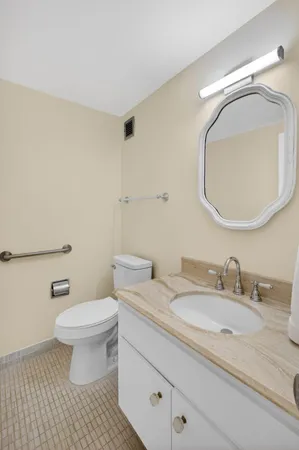 a bathroom with a granite countertop toilet a sink and a mirror