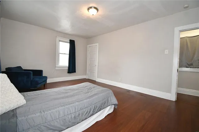 a spacious bedroom with a bed and wooden floor
