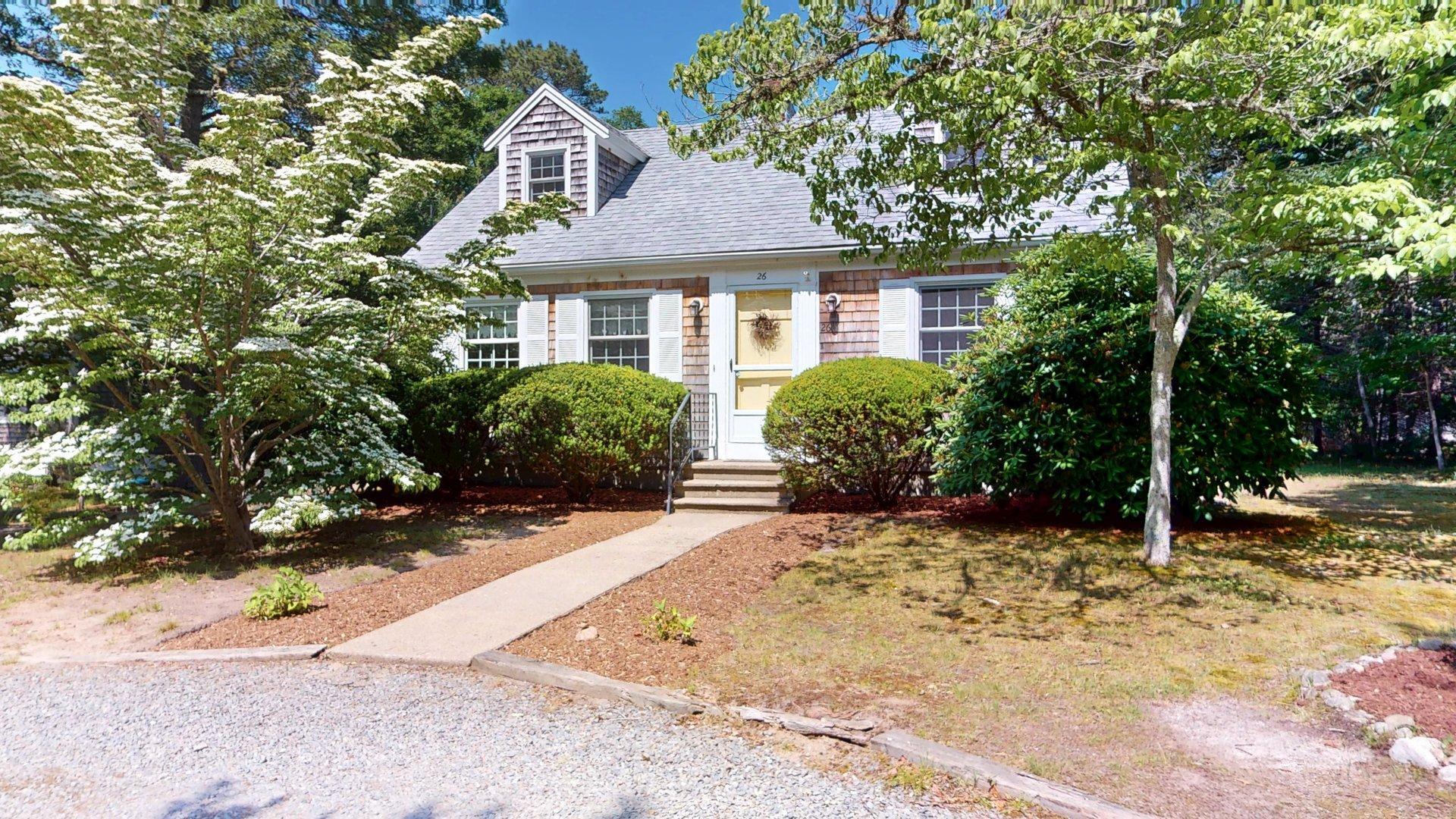 a front view of a house with a yard and potted plants