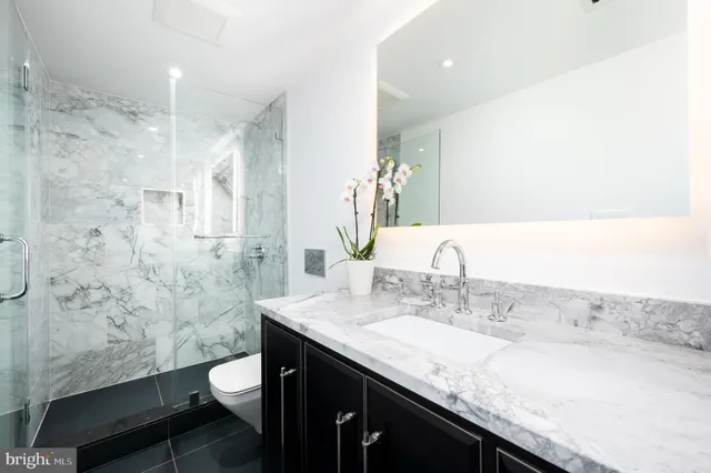 a bathroom with a granite countertop sink a toilet a mirror and shower