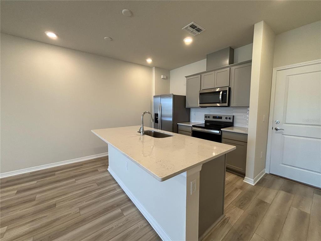 16274 Bright Leaf Road Winter Garden, FL 34787 - Photo 6 of 38 a kitchen with kitchen island a sink dishwasher a stove and a refrigerator with wooden floor