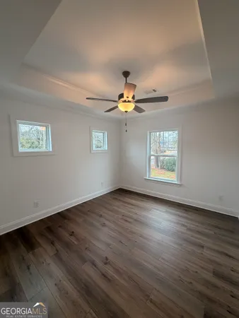 an empty room with wooden floor chandelier fan and windows