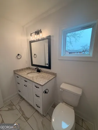 a bathroom with a granite countertop toilet and a sink