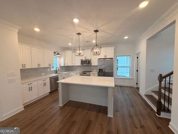 a large room with kitchen island a sink wooden floor white stainless steel appliances and cabinets