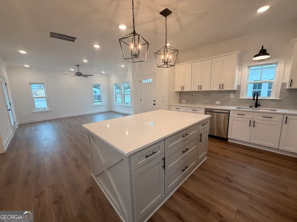 a large kitchen with cabinets a sink dishwasher a dining table and chairs with wooden floor